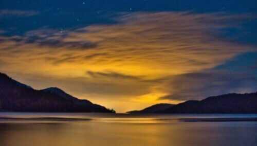 silhouette of mountain near body of water during sunset